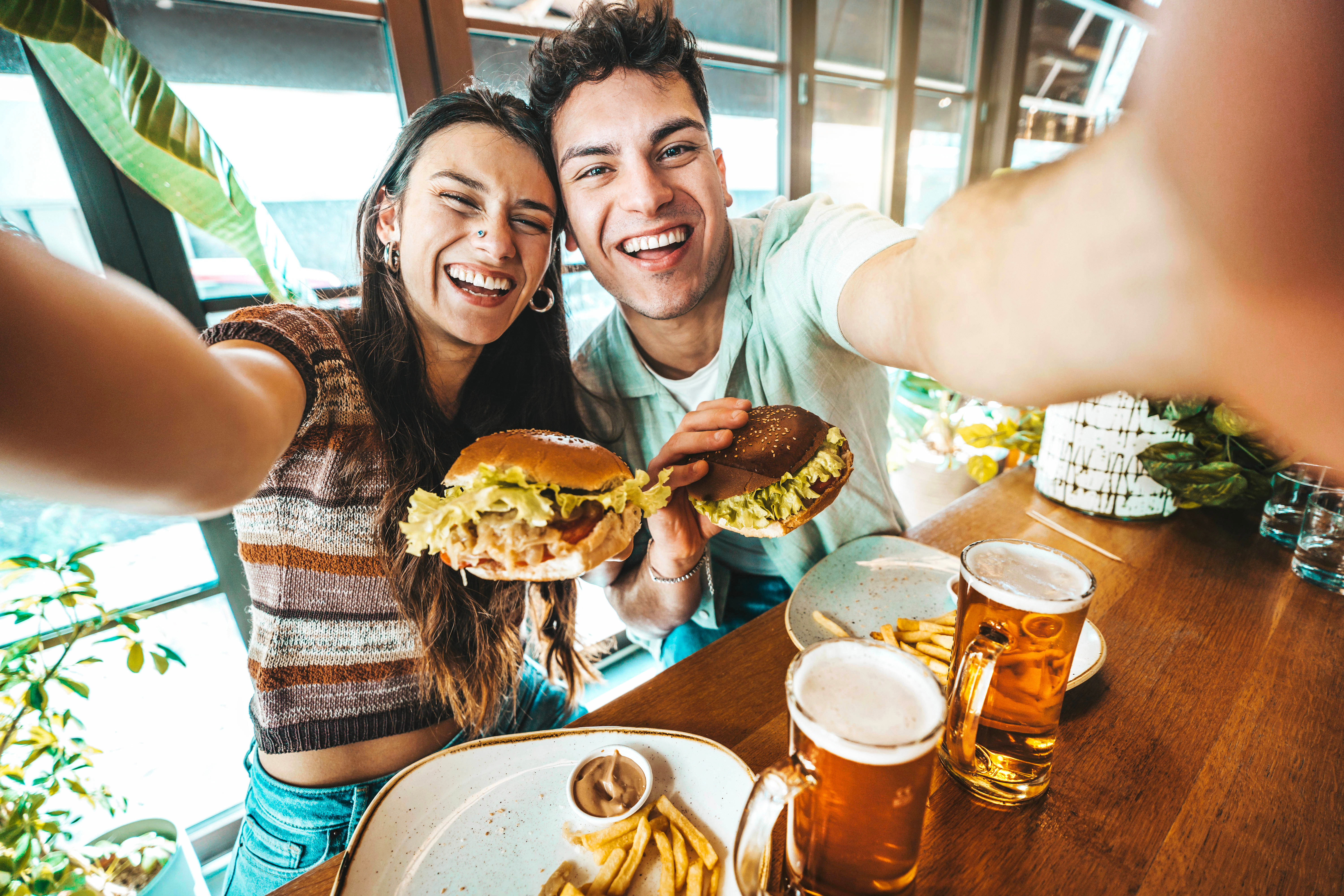 A young couple taking a selfie while eating lunch.