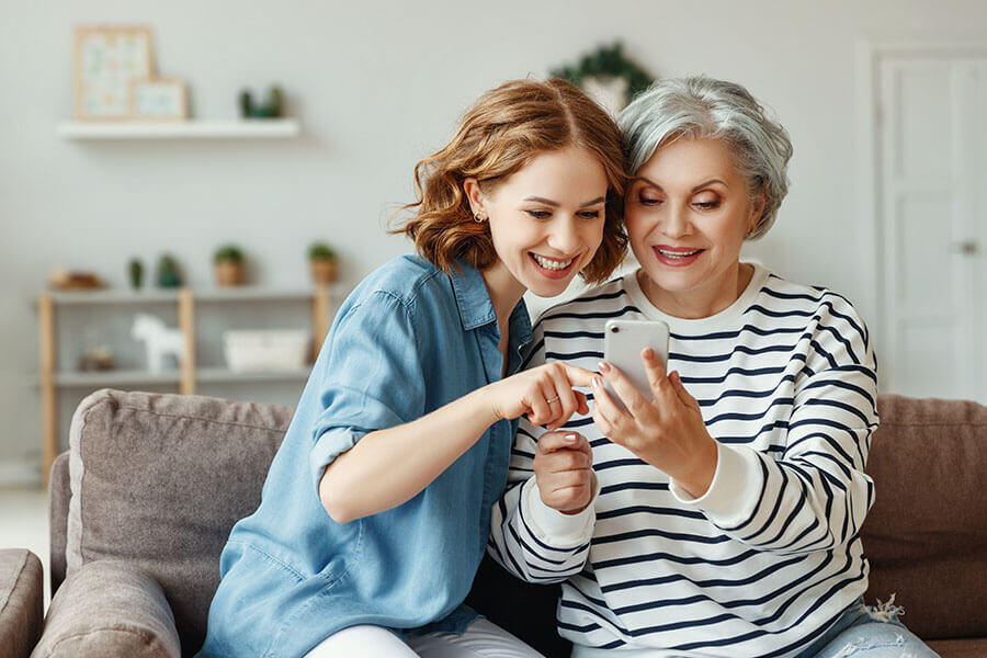 A woman helps her mother check her credit union account on her smartphone.