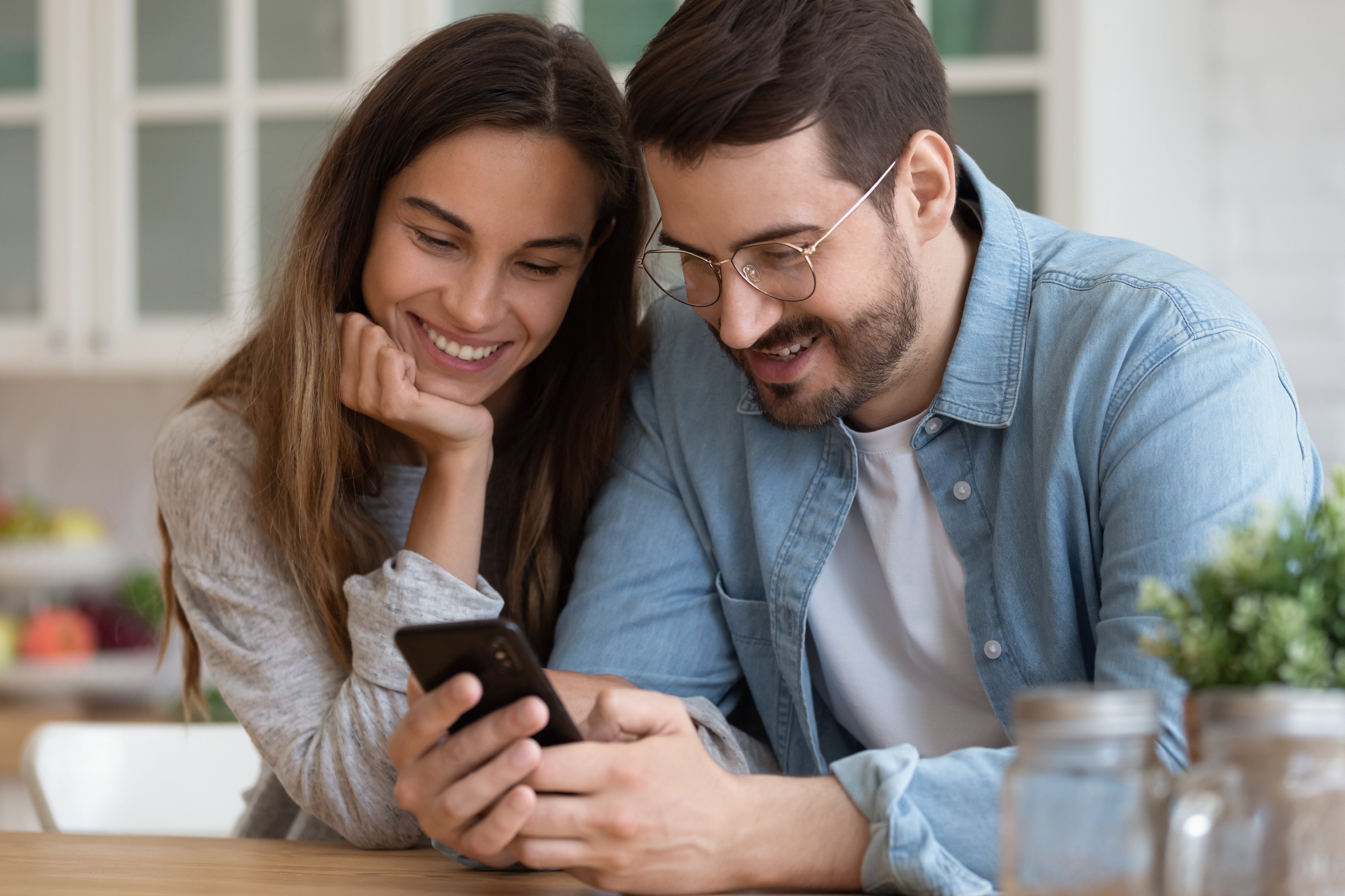 A couple is smiling while they order checks from the comfort of their home using WEOKIE's mobile app.